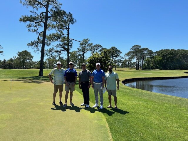 Five veterans posing together on the green