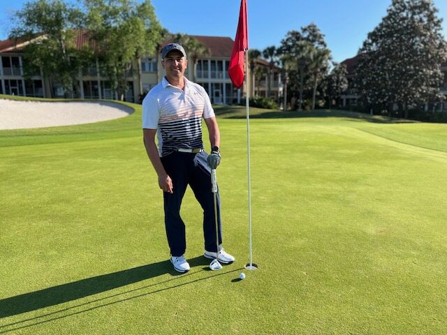 A veteran posing beside the flag on the green
