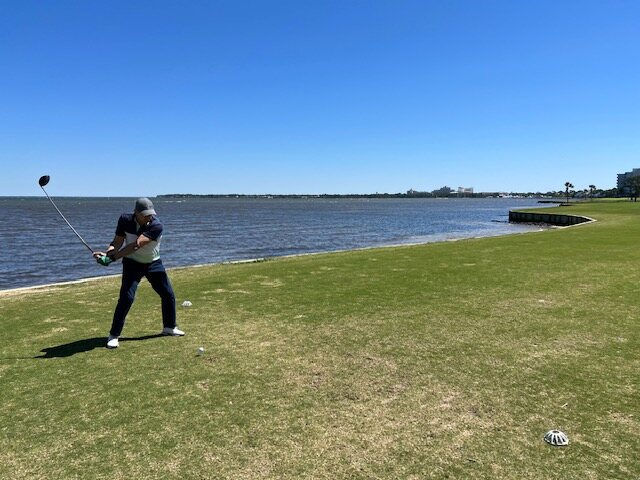 A veteran mid-swing on a tee overlooking the bay
