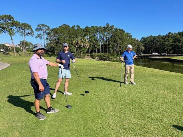 Three veterans on the tee box beside the water