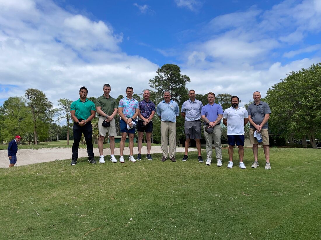 Nine veterans posing together beside a bunker