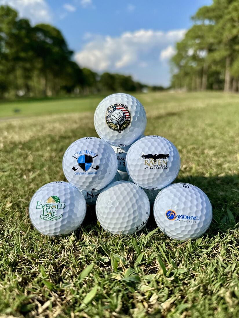 A pyramid of golf balls branded with the logos of Links of Valor, The Links, Raven, Emerald Bay, and Baytowne