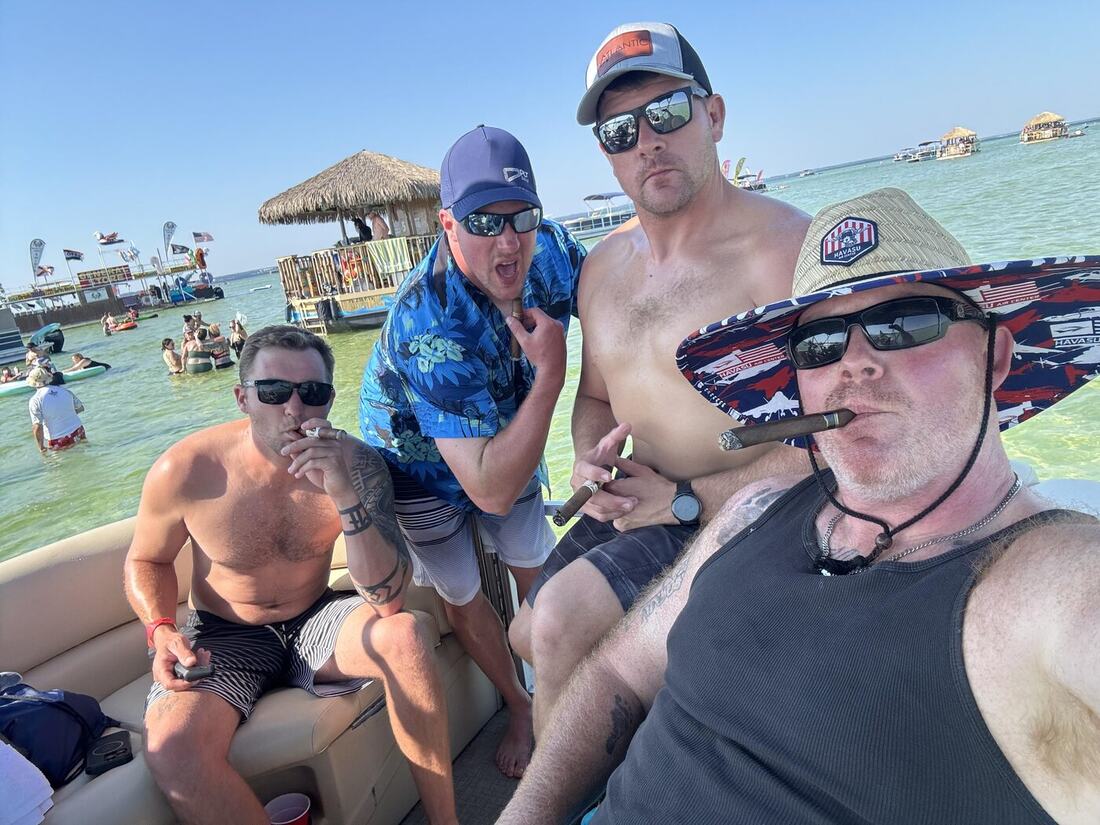Veterans relaxing with cigars aboard a pontoon boat on the bay