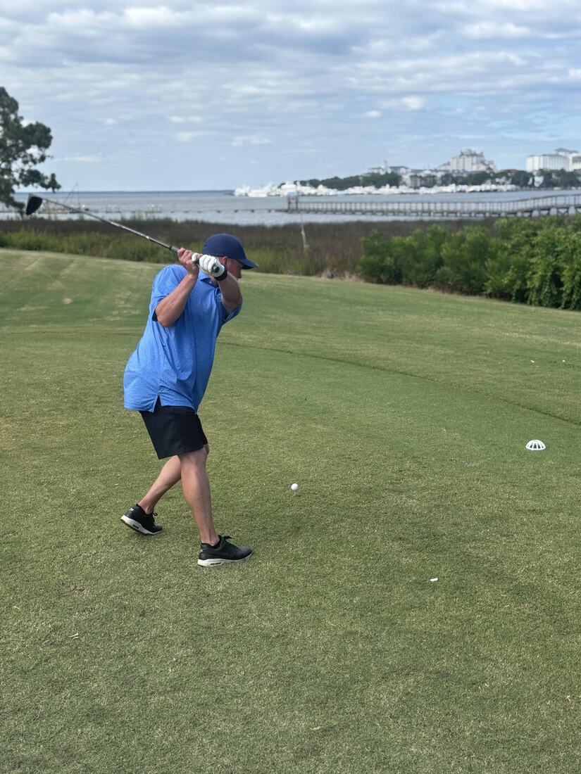 A veteran teeing off beside the bay