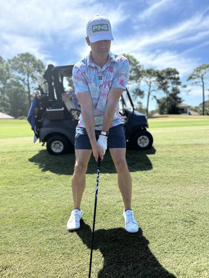 A veteran teeing off beside the golf cart